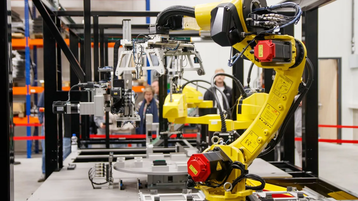 Yellow industrial robot arm and gripper in an automated assembly cell